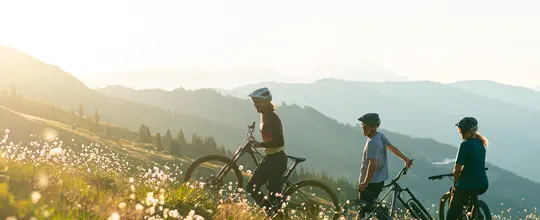 drei Personen stehen mit Fahrrad in der Wiese
