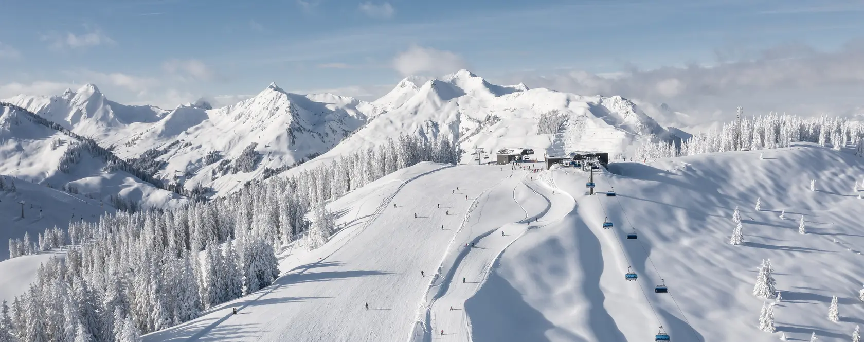 Snowy mountain landscape with ski slopes and lifts under a blue sky