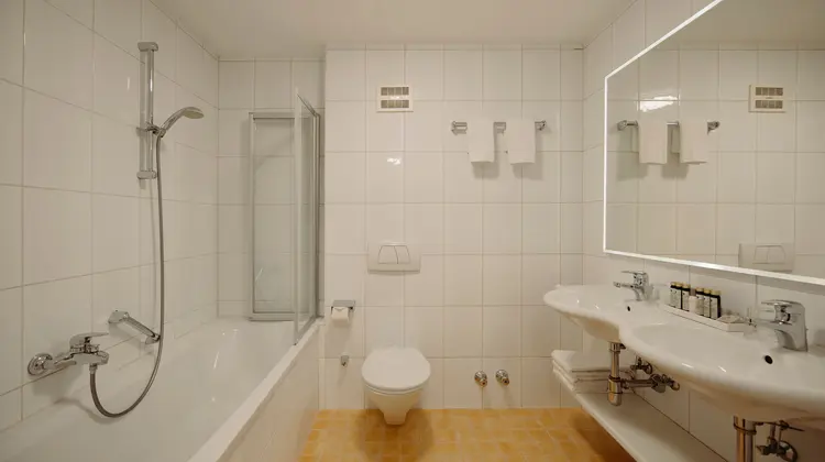 Salle de bain lumineuse avec baignoire, douche, toilettes et lavabo