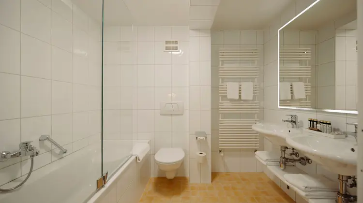 Bright bathroom with shower, toilet, sink and towel warmer