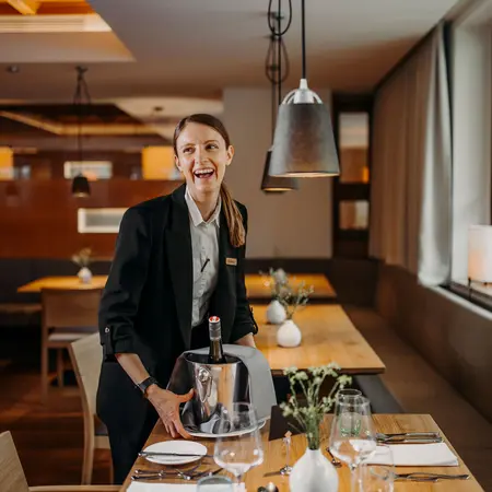 Lachende Kellnerin mit Weinkühler in Restaurant