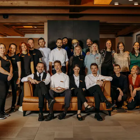 Gruppenfoto des GHT-Teams stehend und sitzend auf einem Ledersofa