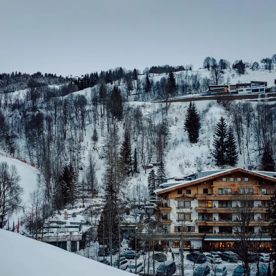 Gartenhotel Theresia im Winter am verschneiten Hang mit Bäumen und Skipiste