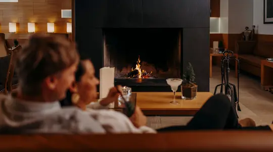 Couple in front of fireplace with cocktail glasses on table