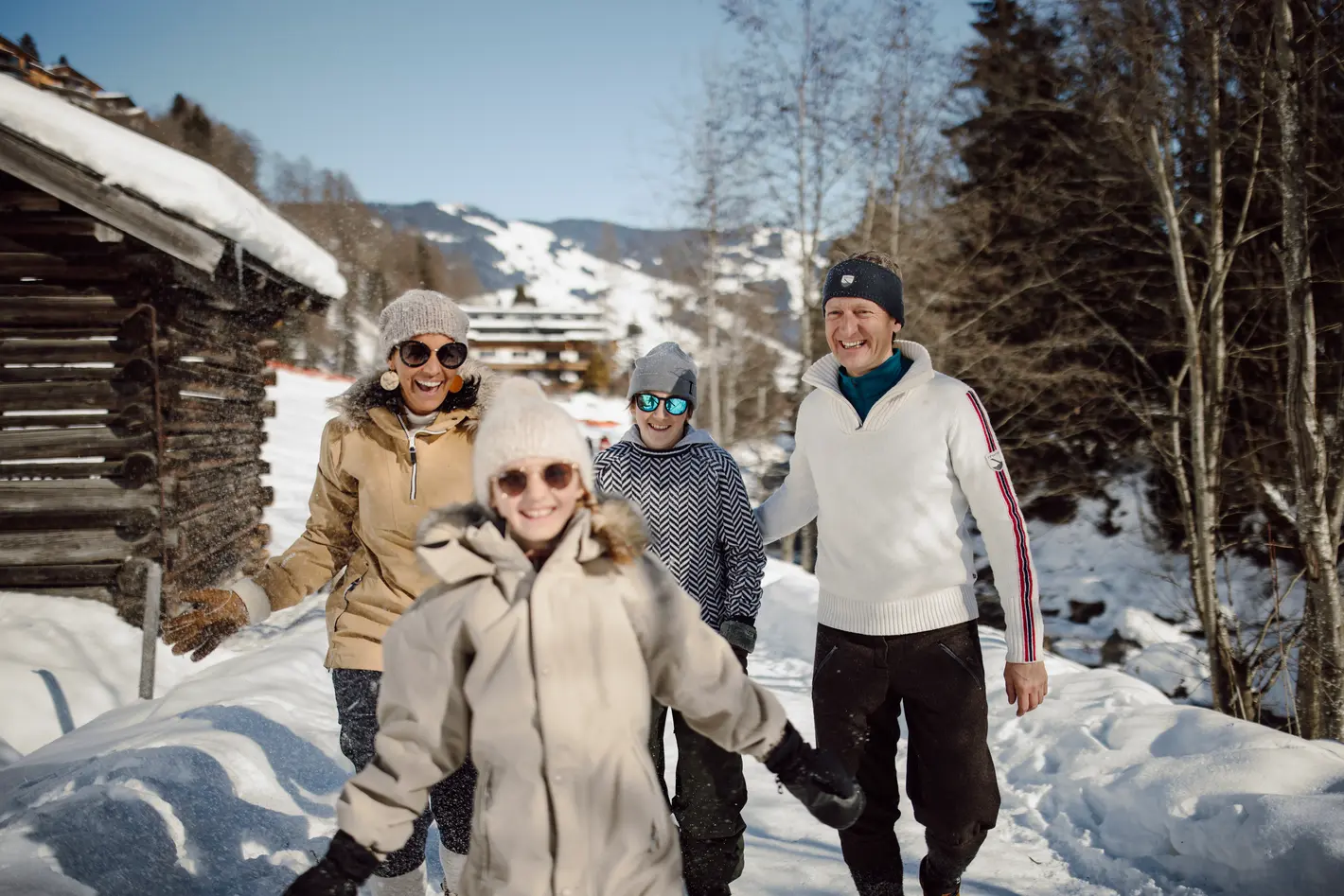 Familie mit Winterkleidung und Sonnenbrillen im Schnee vor Bergkulisse
