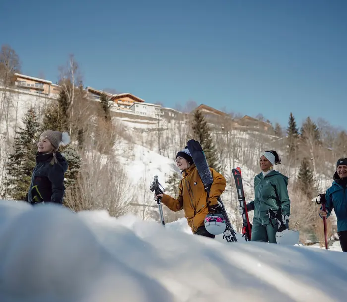 Group of young people with skis and snowboard in the snow in front of mountain scenery