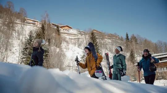 Group of young people with skis and snowboard in the snow in front of mountain scenery