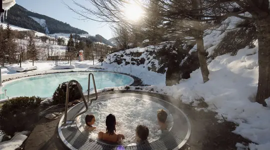 Winter landscape with steaming whirlpool and bathers in the foreground