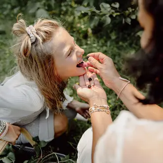 Mutter und Tochter beim Beeren essen im Wald
