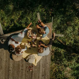 Familie beim Picknicken auf der Holzterrasse im Wald