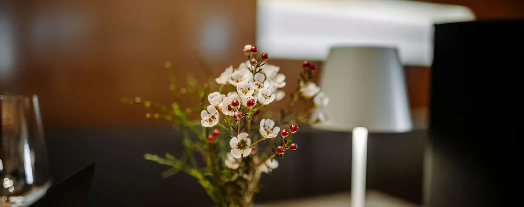 Blumenstrauß in weißer Vase neben einer Lampe auf einem Tisch