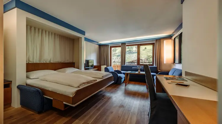 Hotelzimmer mit Doppelbett, Sitzecke und Schreibtisch vor Fenster mit Bergblick
