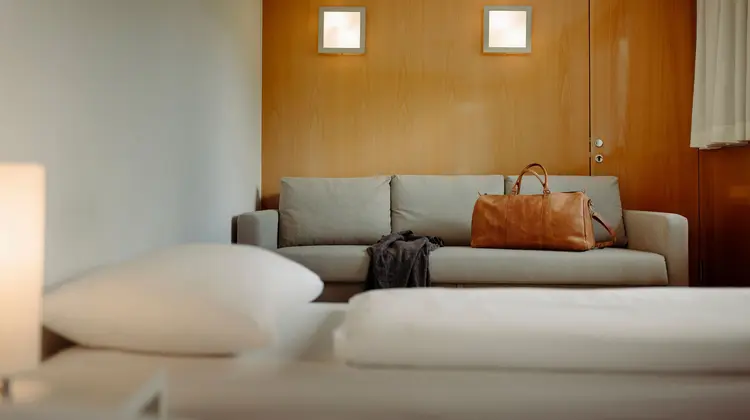 Pièce lumineuse avec canapé, sac de voyage et deux appliques murales