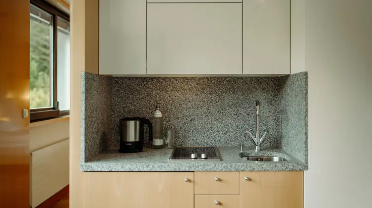 Petite kitchenette avec évier, plaque de cuisson, bouilloire et placards clairs